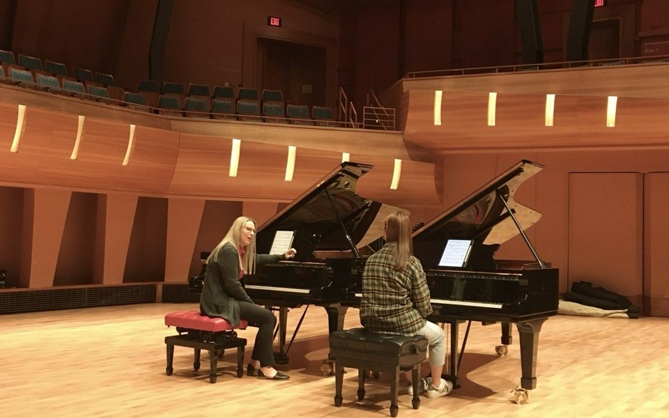 Dr. Lana Henchell teaching a student at two grand pianos.